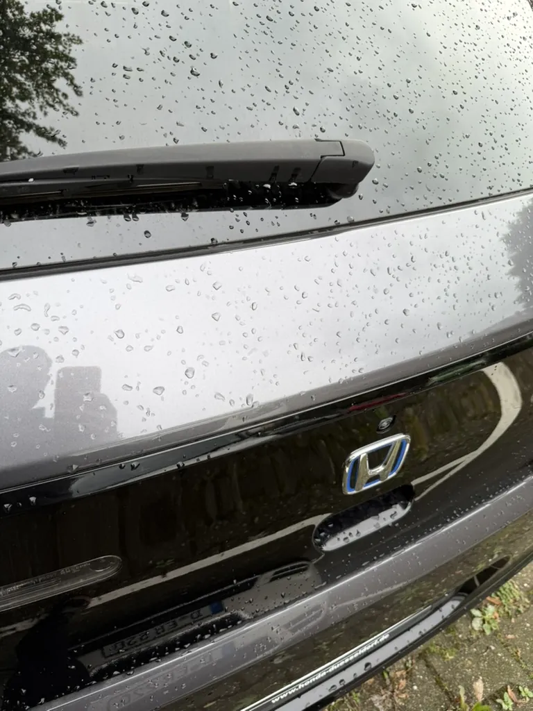 Nasses Fahrzeugheck, auf dessen Oberfläche eine Delle ohne Hilfsmittel schwer zu erkennen ist