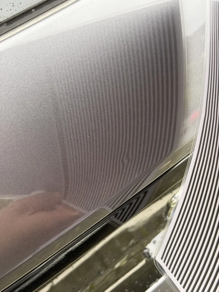 Gestreiftes Dellenreflektor-Muster spiegelt sich auf einem Fahrzeugseitenteil